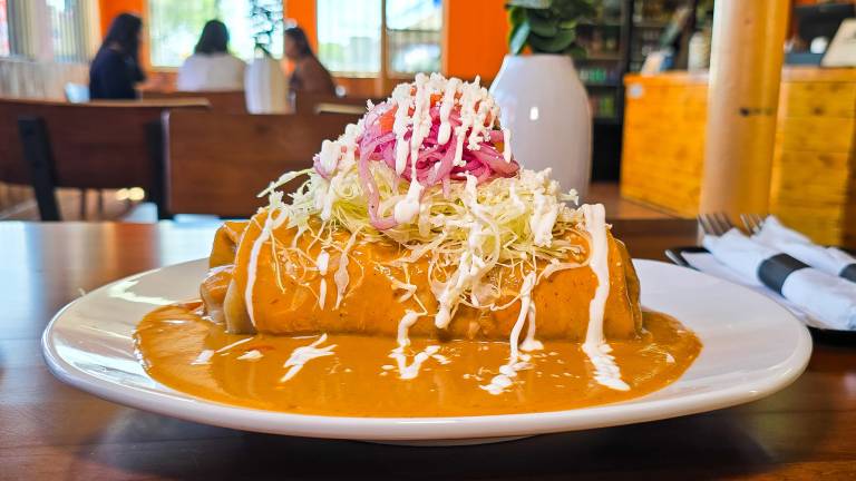 Burrito smothered in orange sauce on a plate.