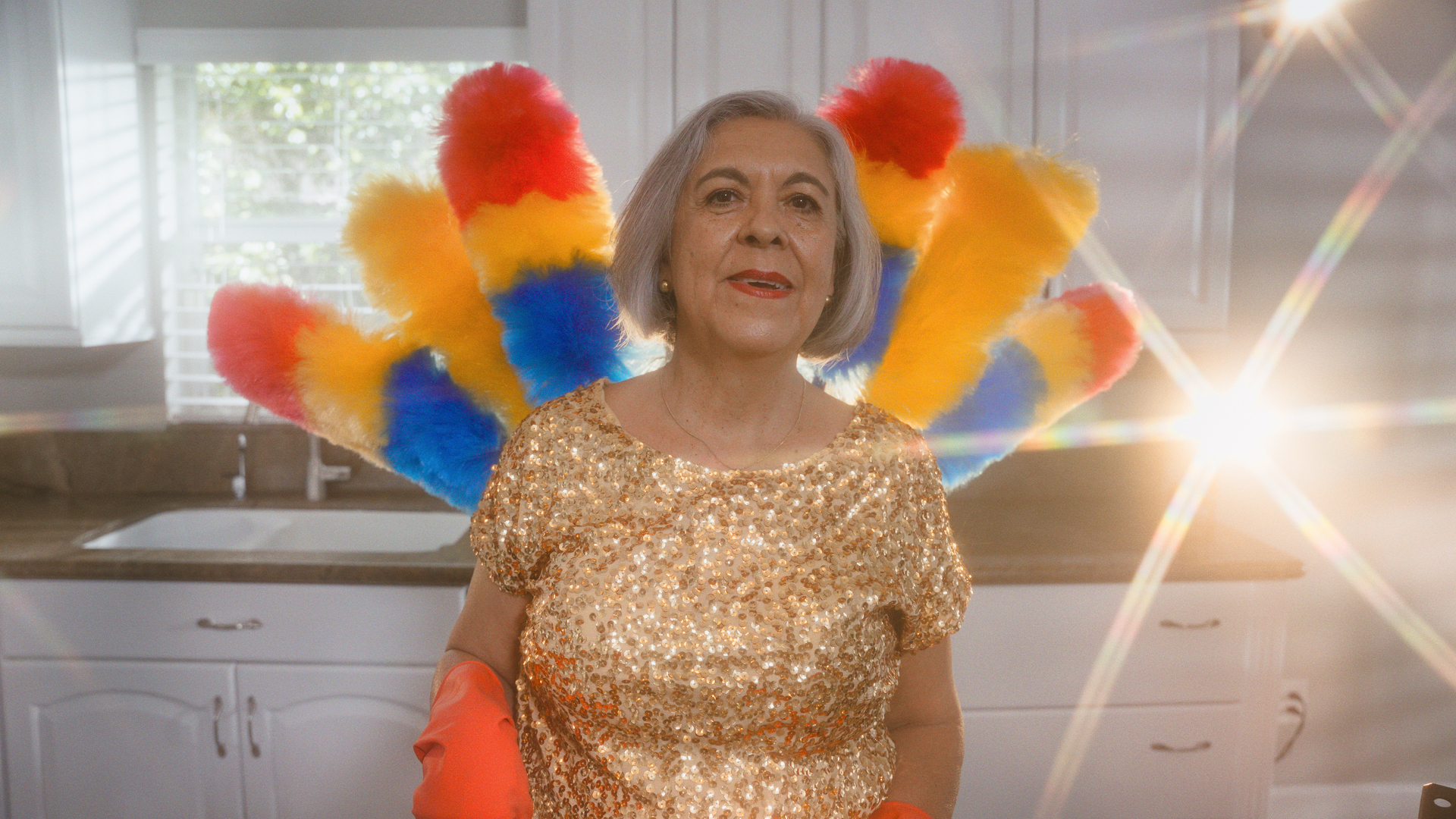 older woman in sequined shirt backed by colorful fan of dusters