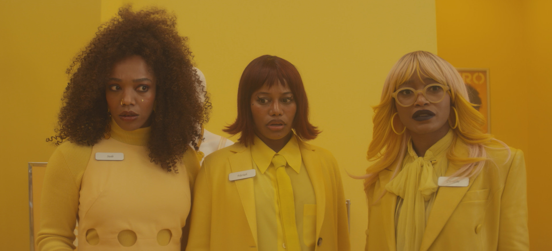 three Black women dressed in all yellow look surprised