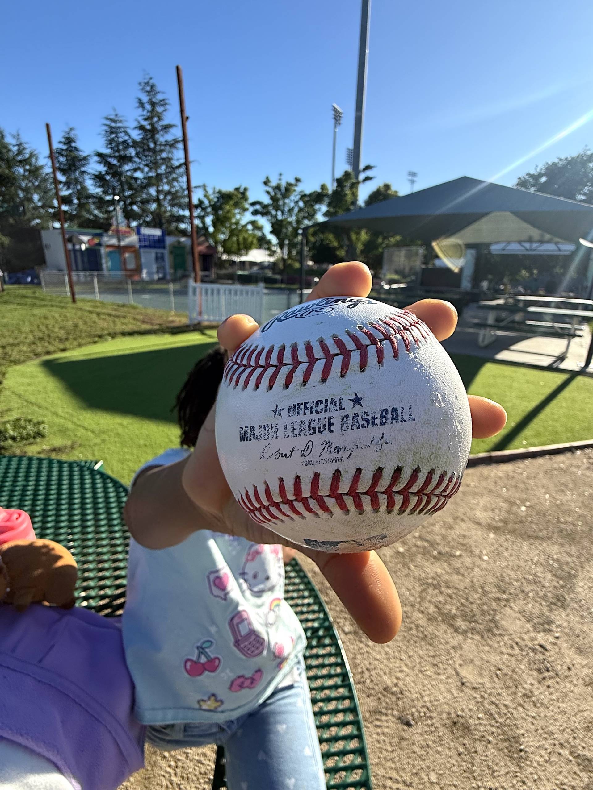 A kid holds an official Major League Baseball up at an A's game in Sacramento.