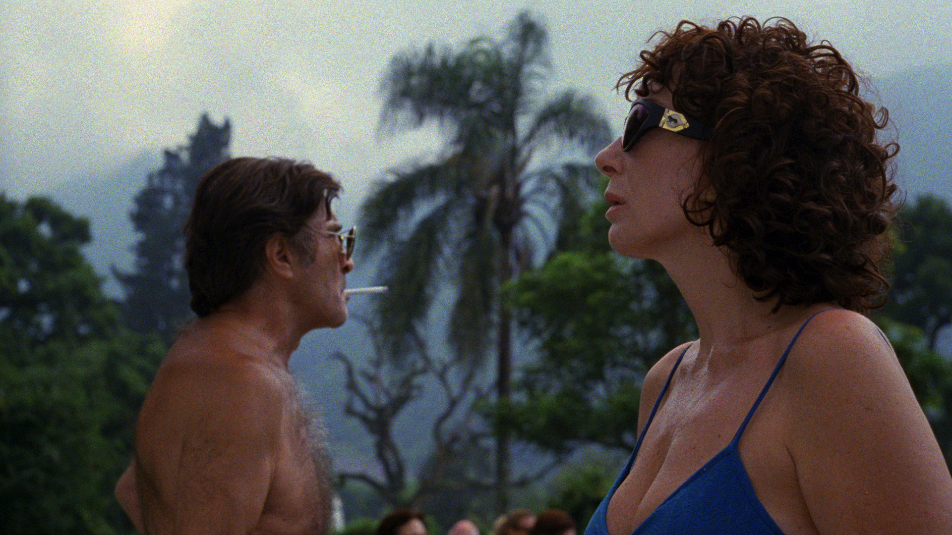 man and woman in profile in swim attire with palm trees in background