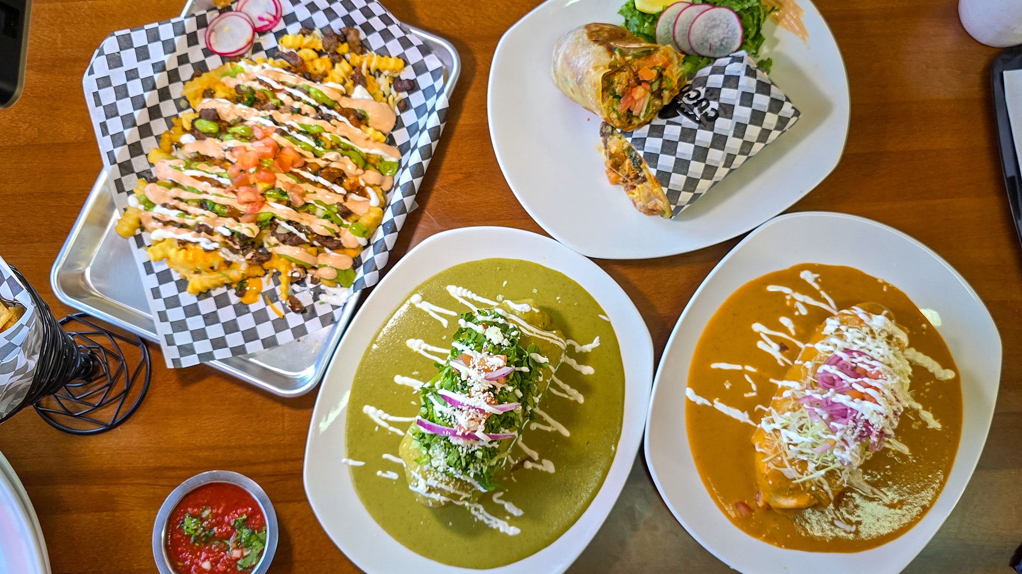 Overhead view of a spread of burritos and carne asada fries.