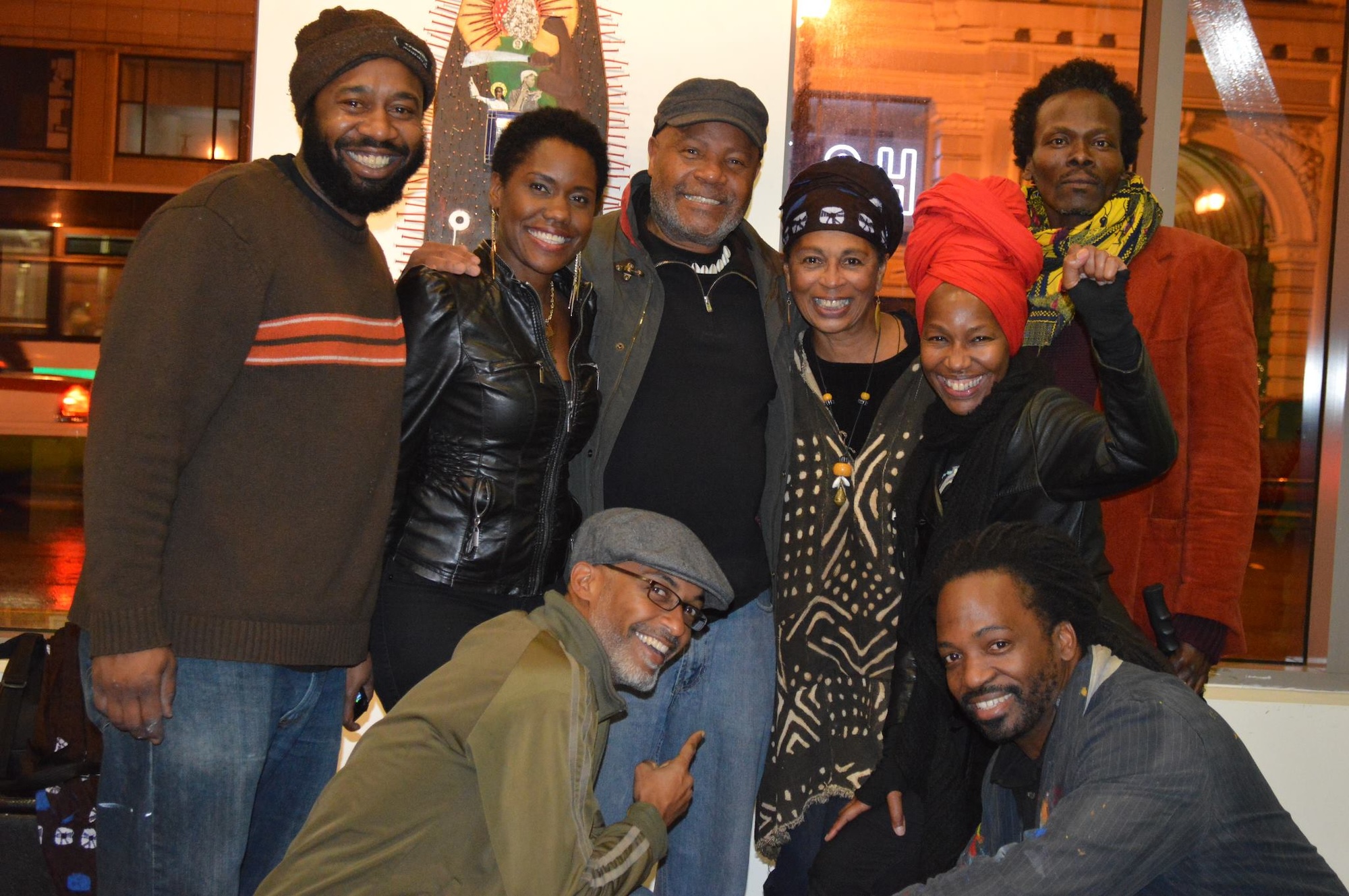 Eight people gather to take a photo inside of an art gallery. 