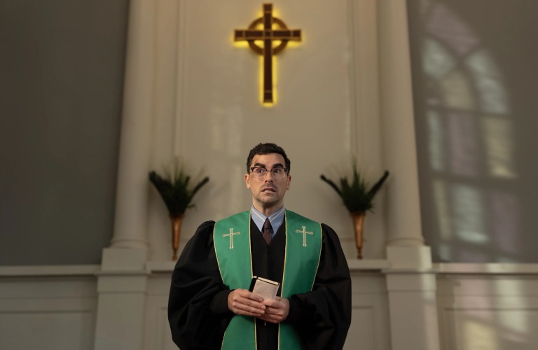A young pastor wearing glasses stands before his congregation looking perturbed.