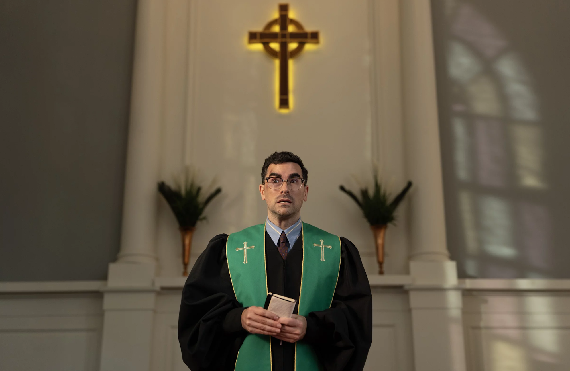 A young pastor wearing glasses stands before his congregation looking perturbed.