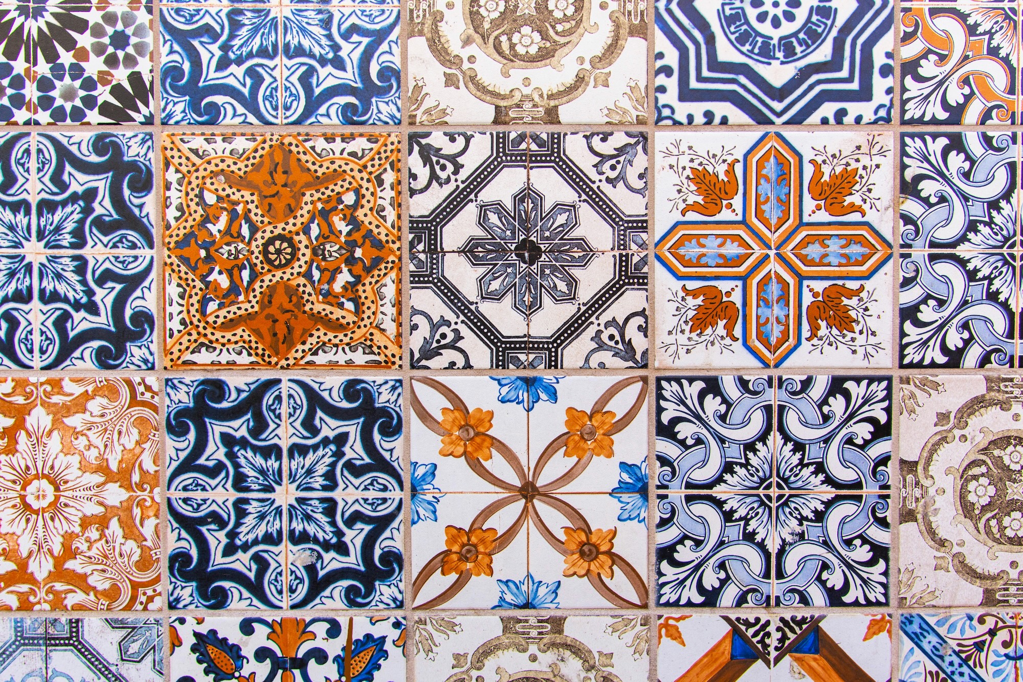 A wall of colorful Portuguese tiles in different blue, white and red geometric patterns.