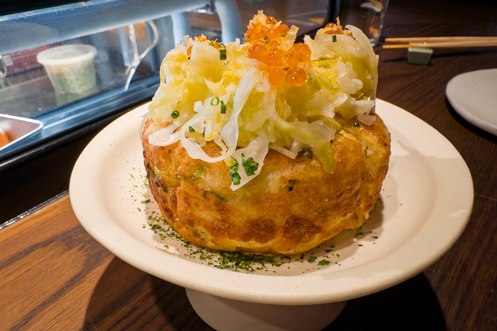 A puffy savory pancake topped with cabbage and orange fish roe.
