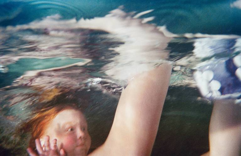 underwater image of adult arms and swimming child