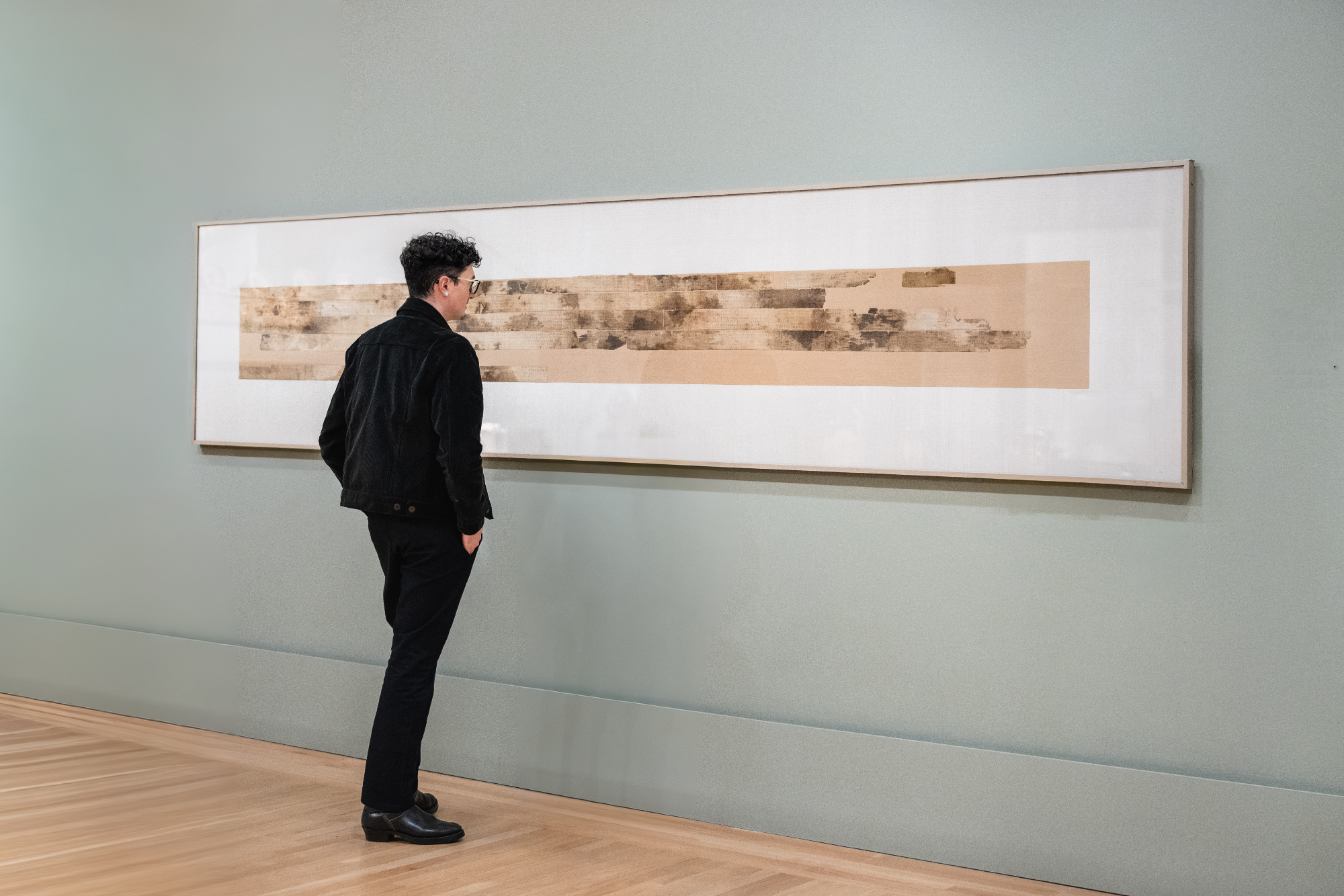 person stands in front of wide frame holding strips of linen