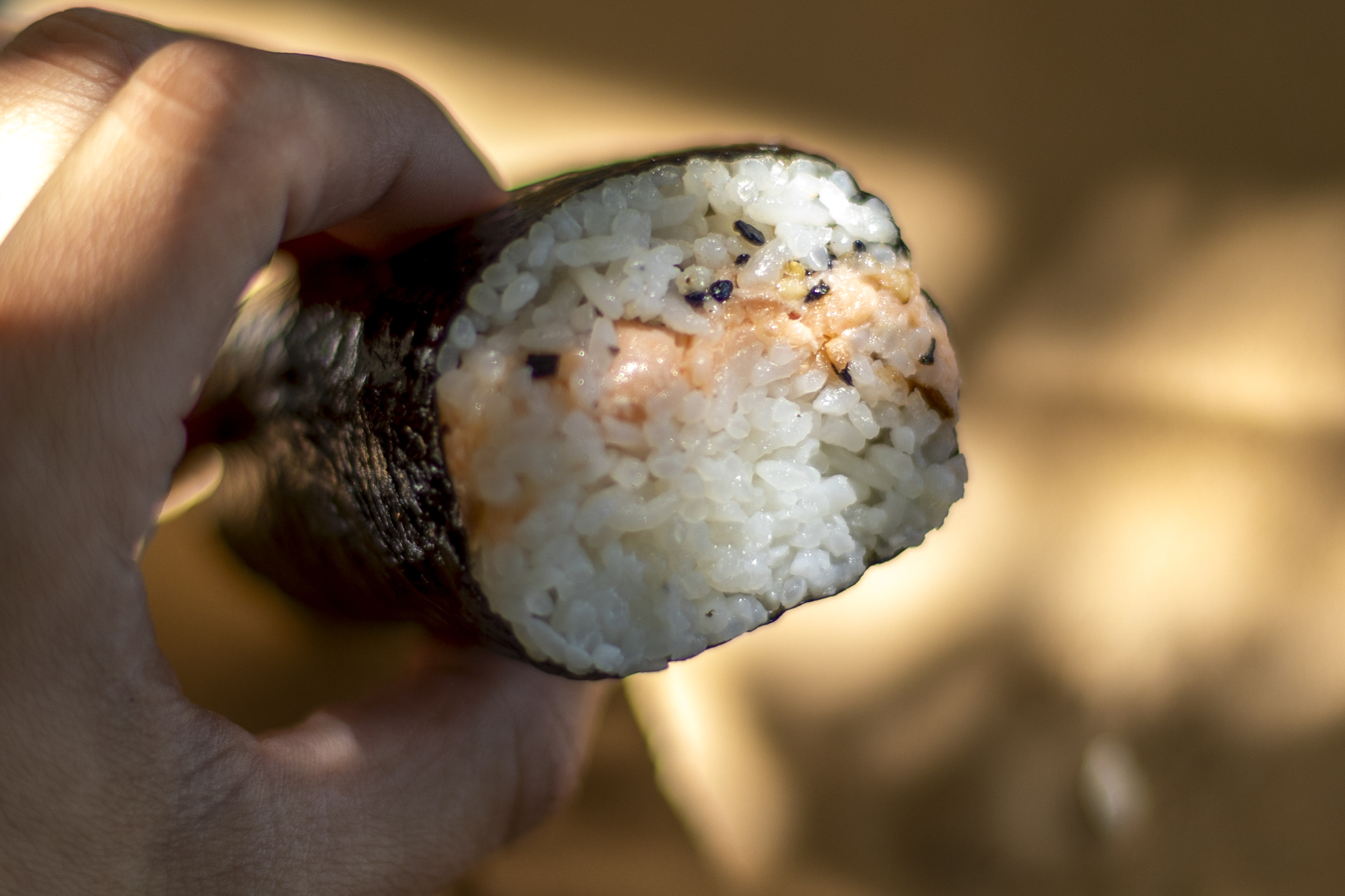 Hand holding a salmon musubi.
