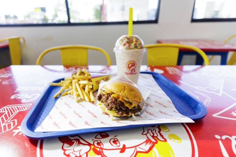 Burger, fries and a colorful, Fruity Pebbles-topped milkshake on a tray.