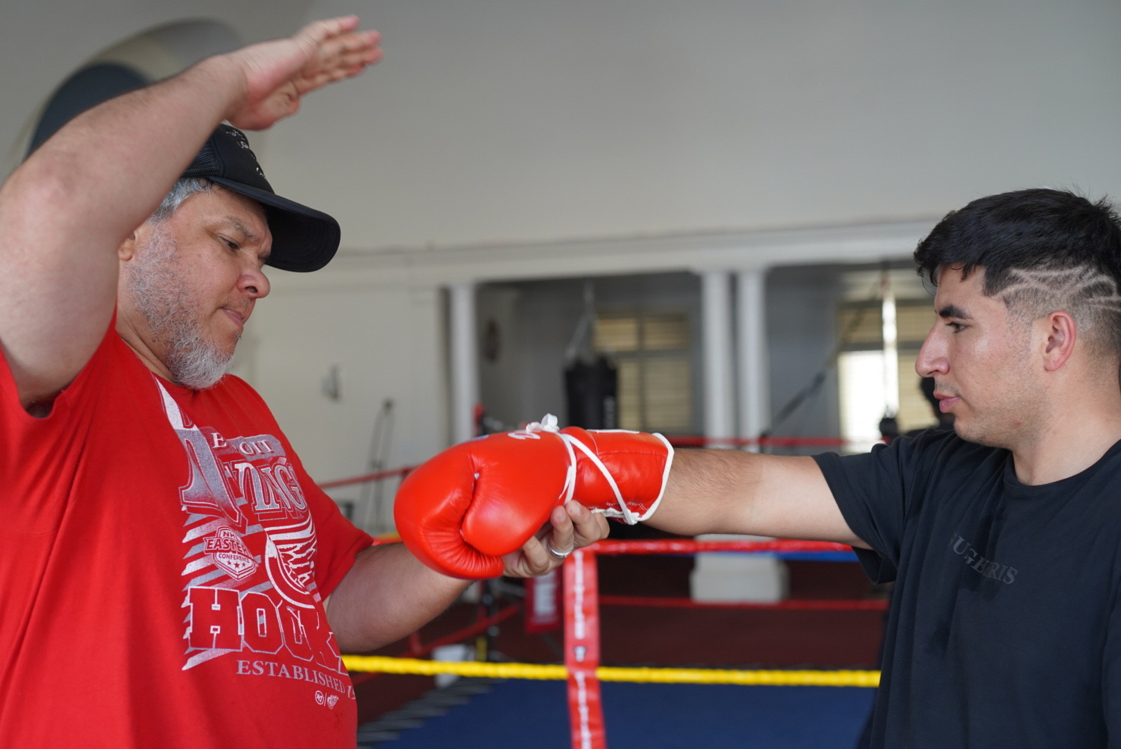A coach and young boxer secure gloves and get ready to train. 