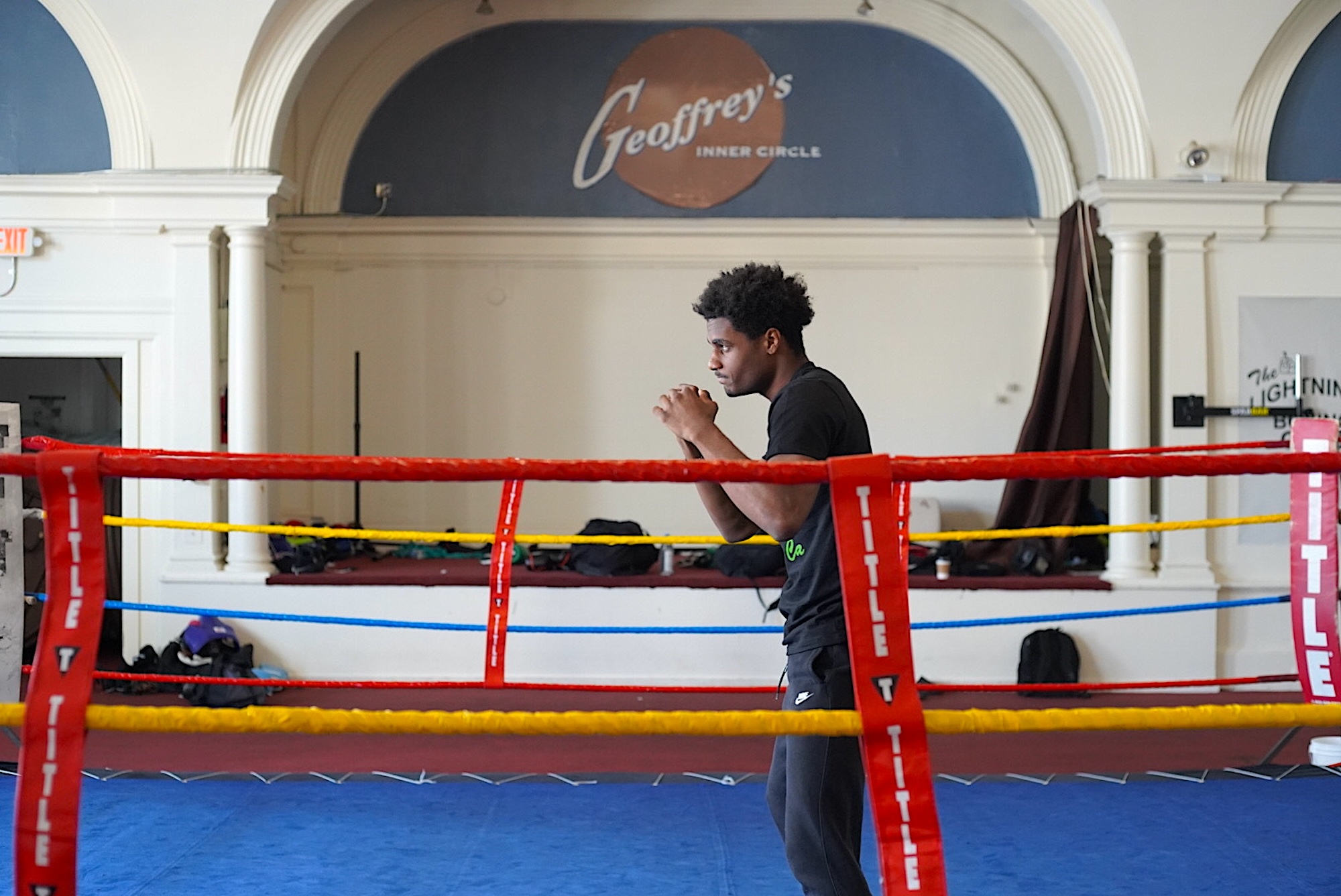 A young African American man shadowboxing in a boxing ring. 