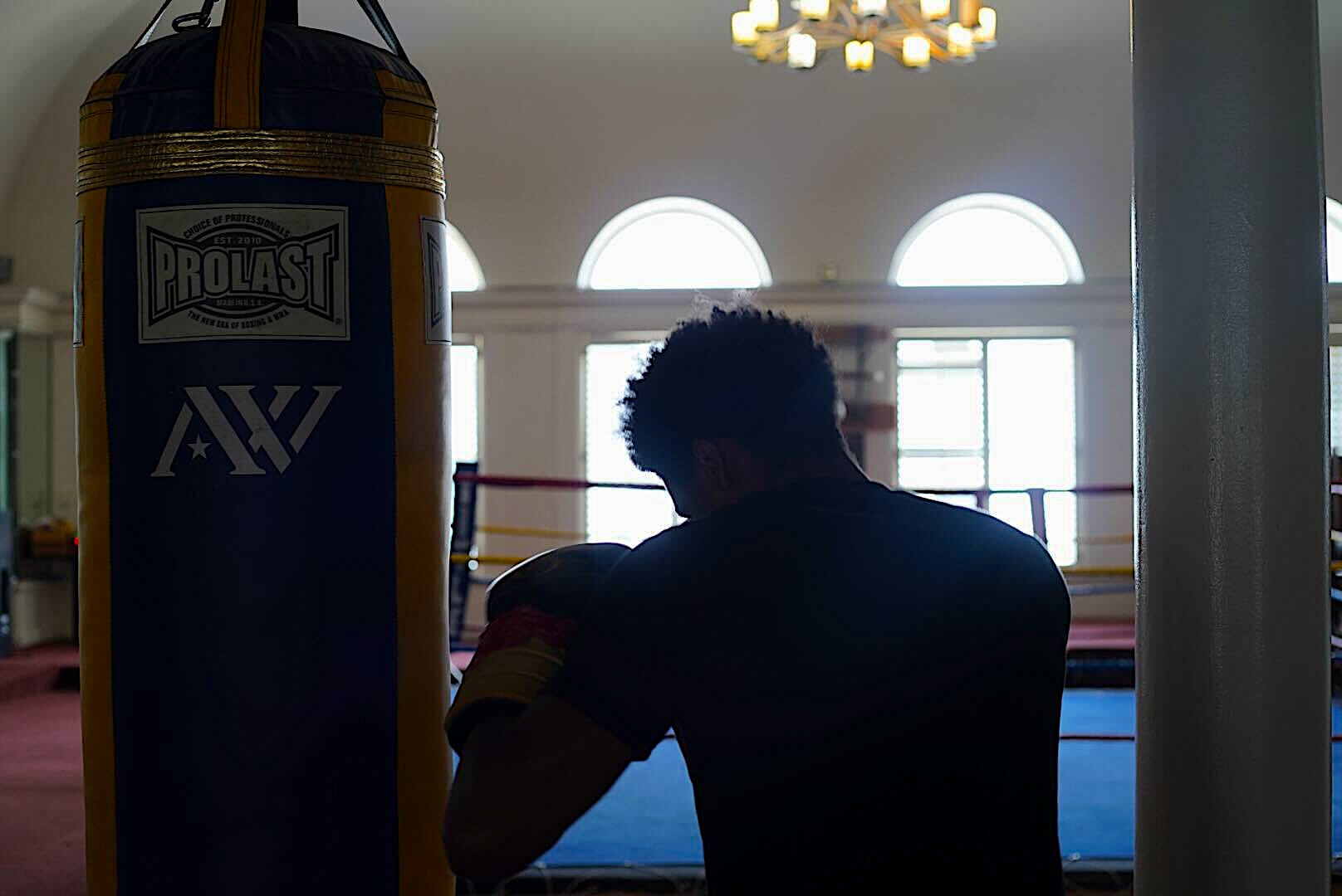 A silhouette of a boxer swinging at a suspended weight bag.