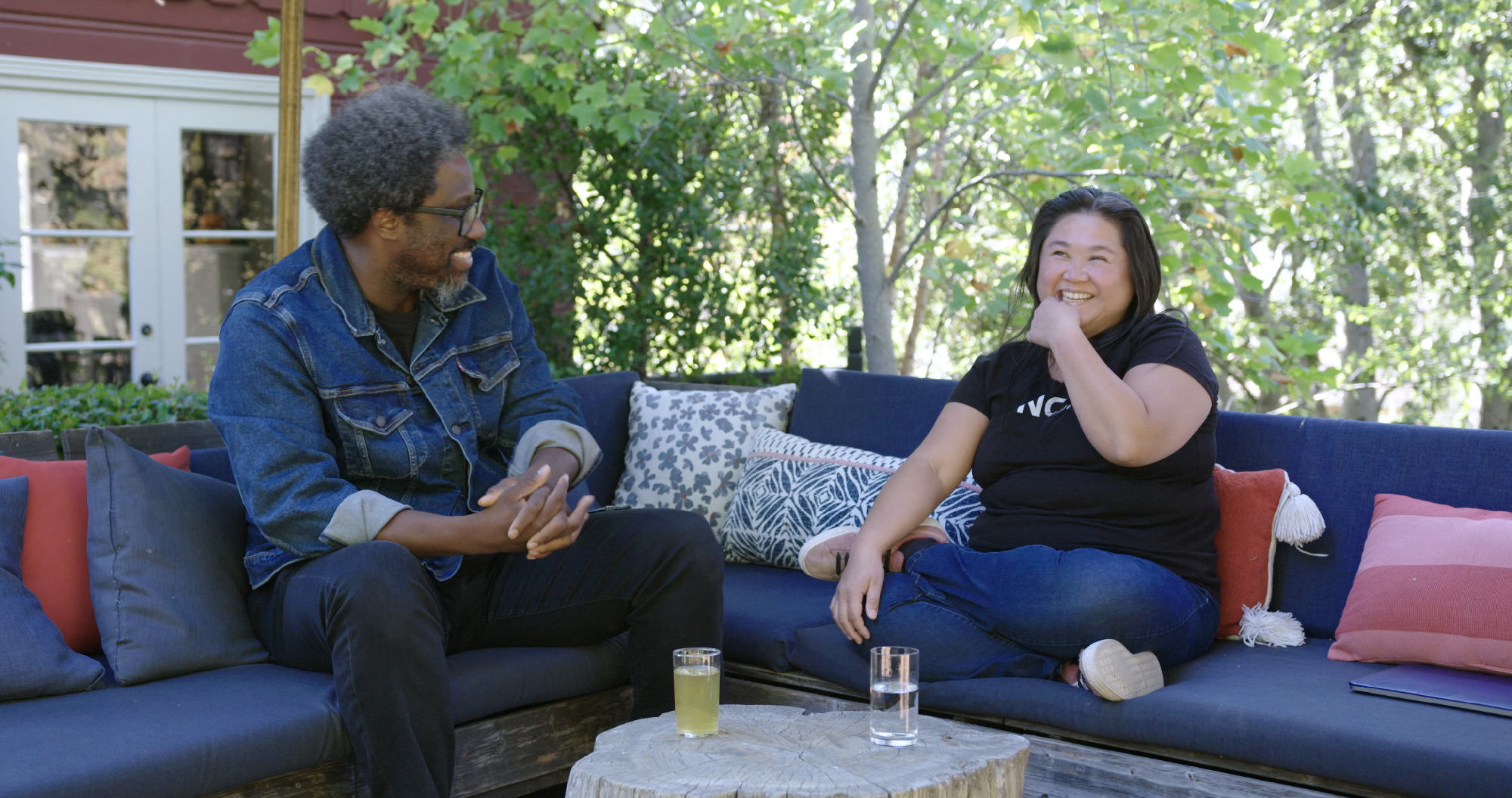 Black man and Asian woman sit on bench and laugh