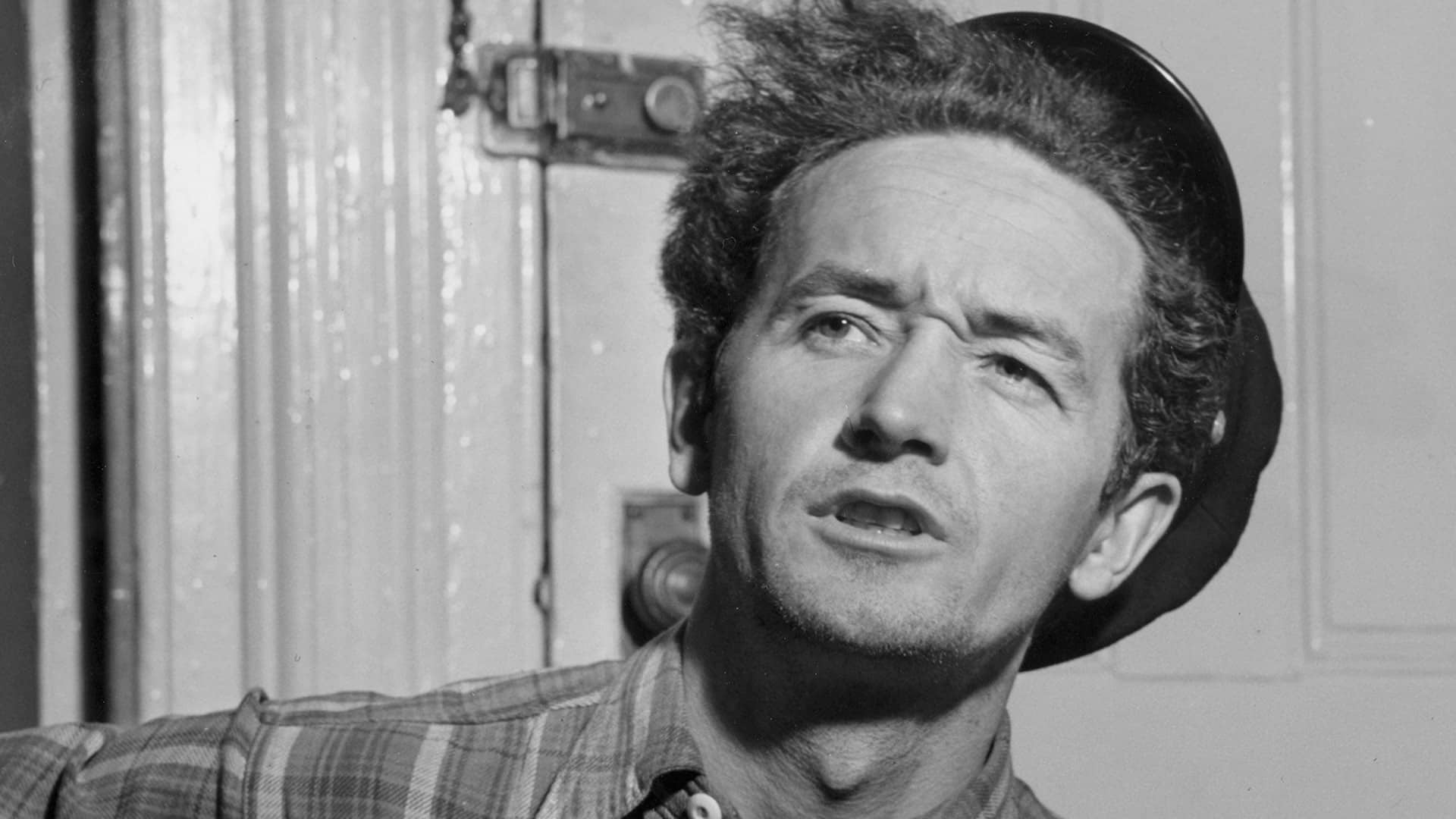 close-up of man with tipped back hat and plaid shirt