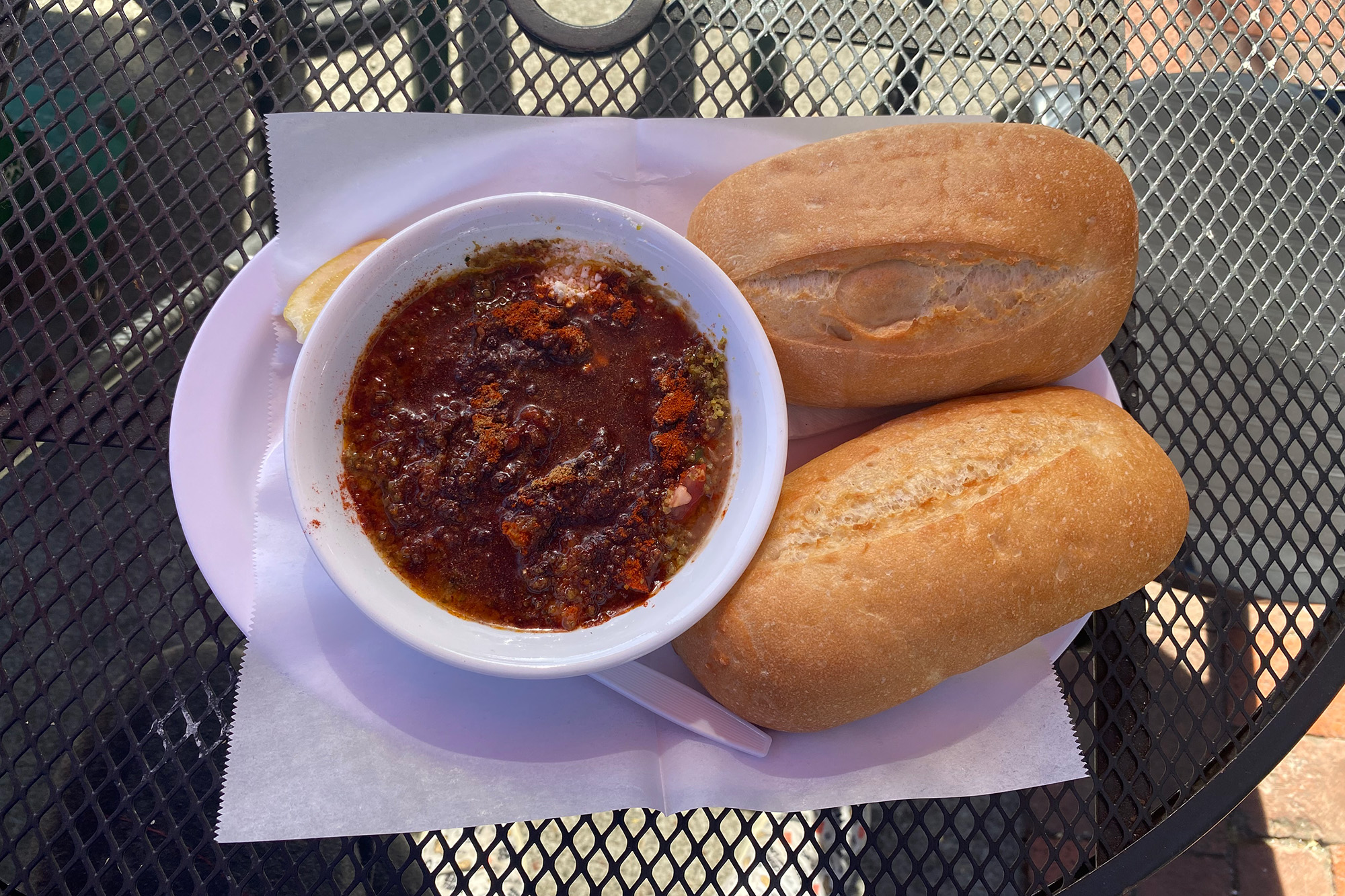 Dark red fava bean stew, with two crusty rolls on the side.