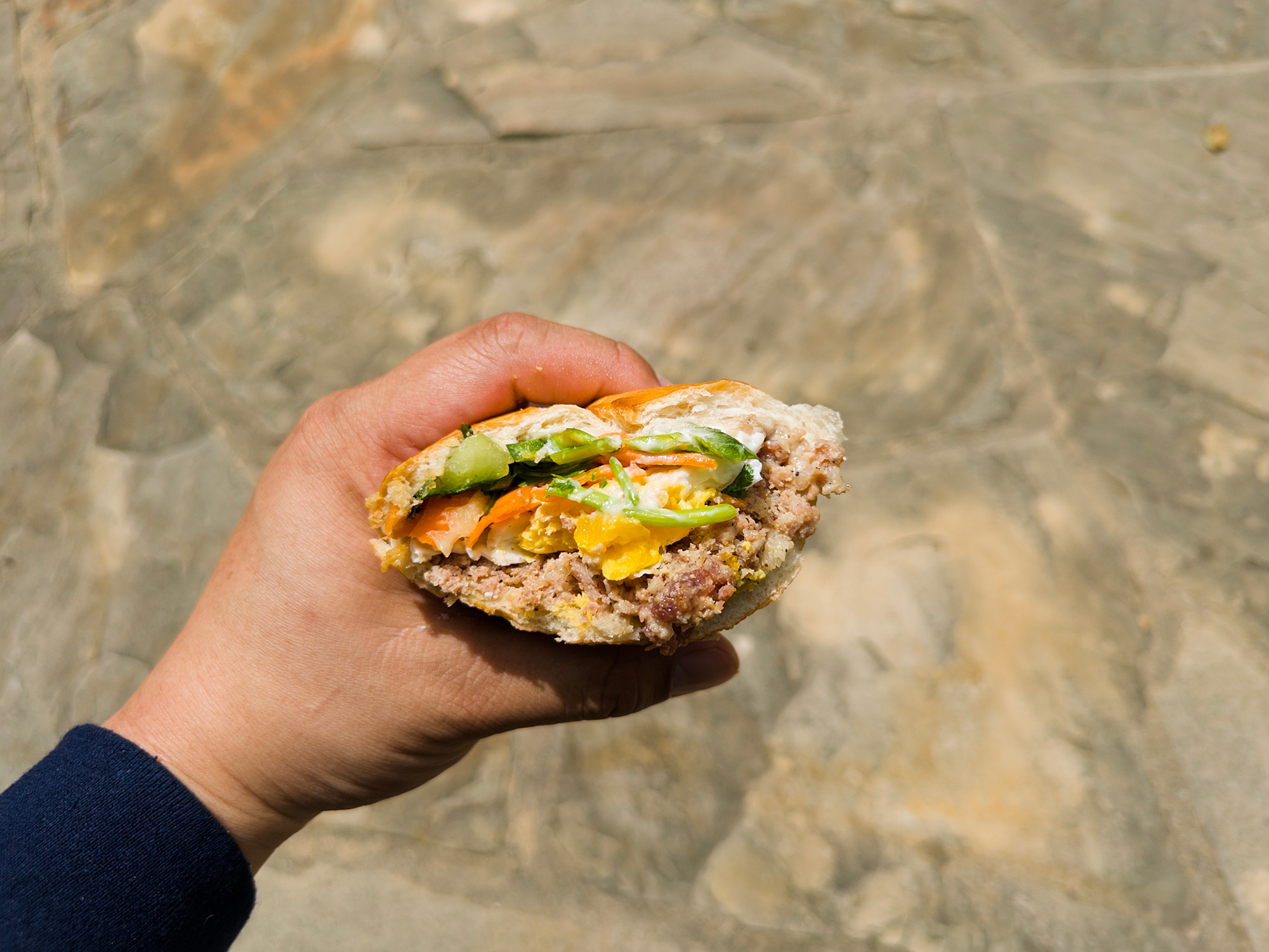 Hand holding what's left of a banh mi sandwich with ground pork and egg.