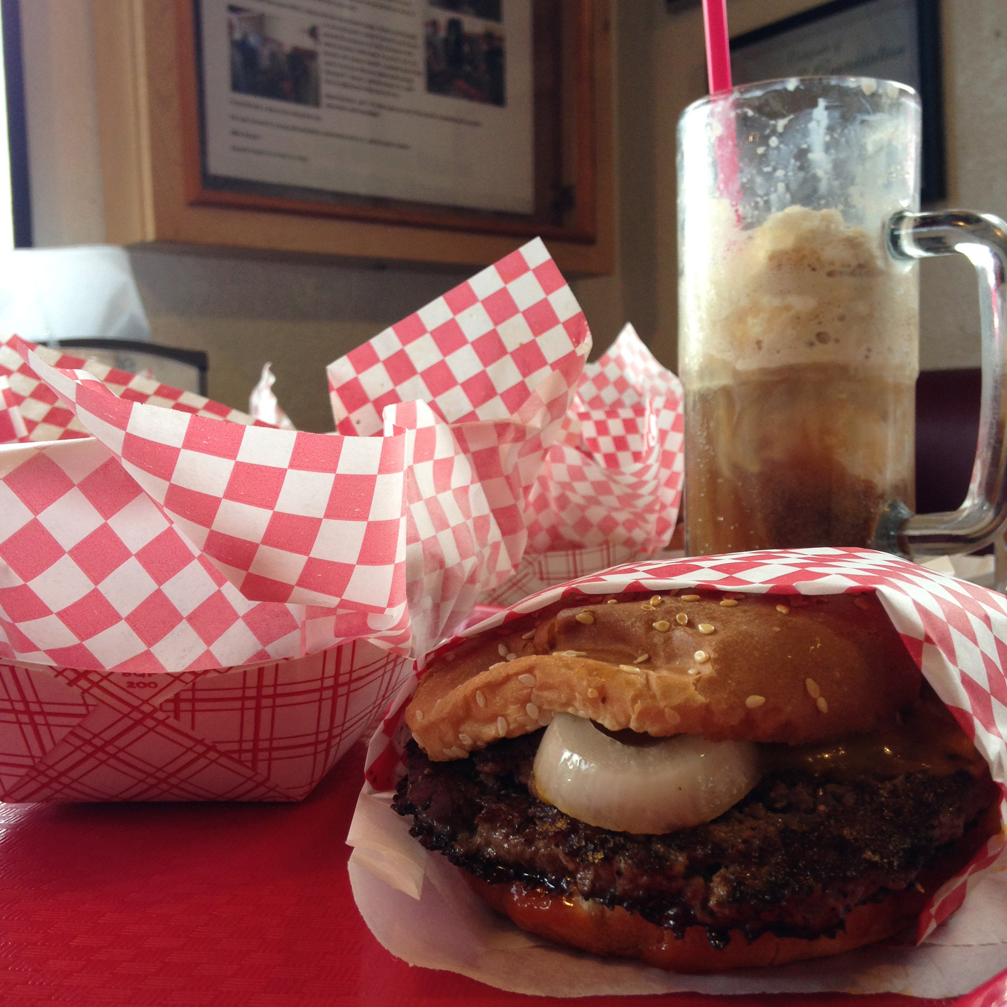 A paper-wrapped burger, a sleeve of fries and a root beer float in a frosty mug.
