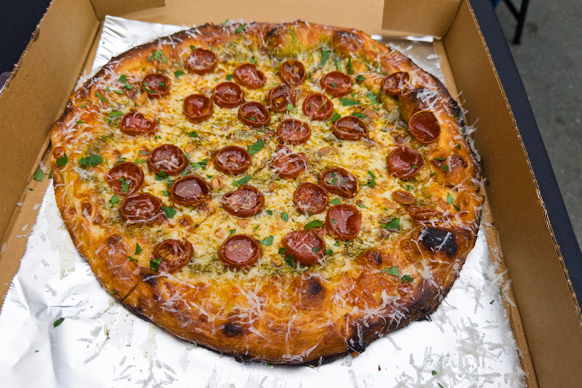 A whole pepperoni pizza inside a foil-lined cardboard pizza box.