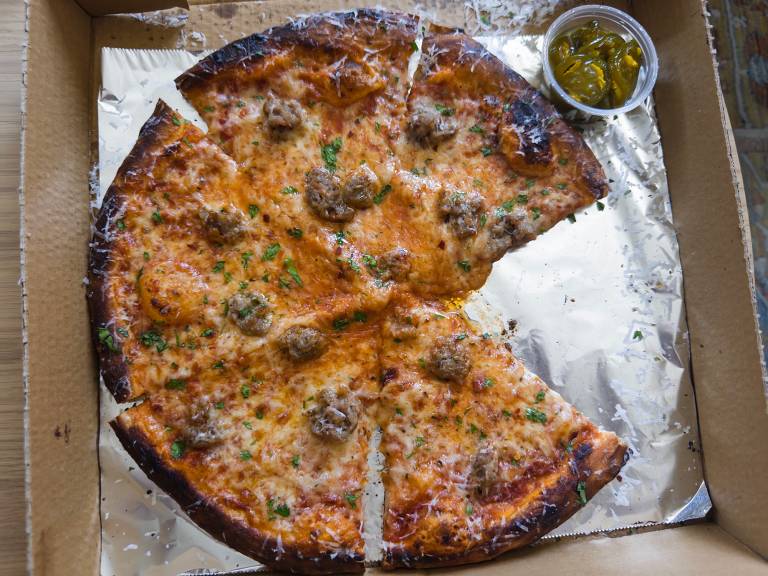 Overhead view of a sausage pizza with one slice missing.