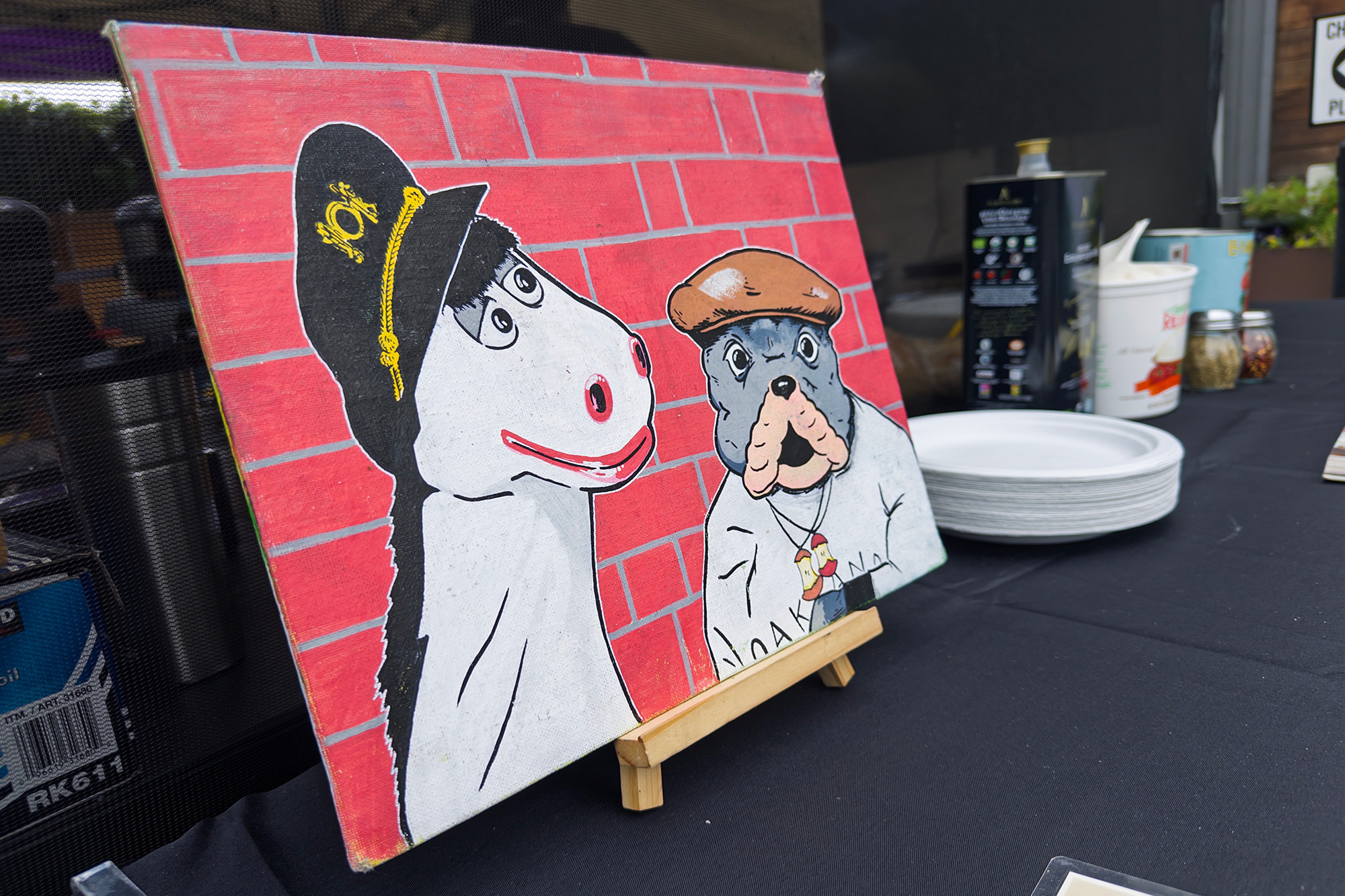 A painting of a cartoon horse and dog propped up on an outdoor table.
