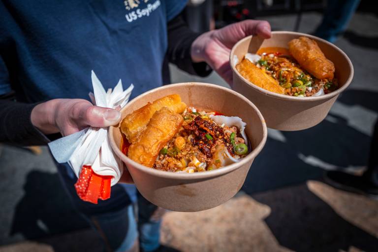 A person holding a bowl of noodles in each hand.