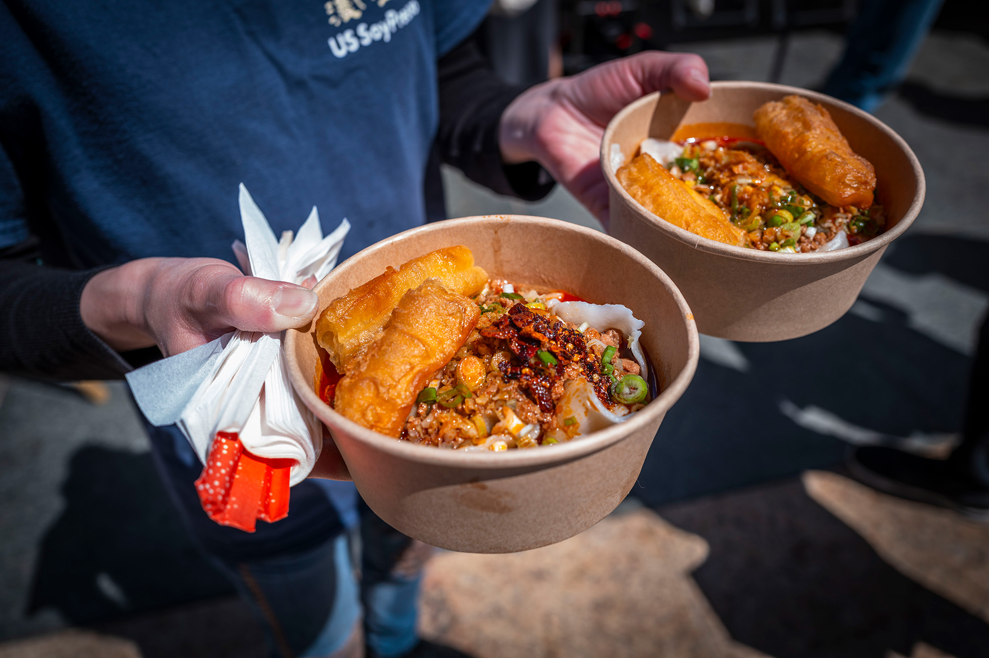 A person holding a bowl of noodles in each hand.