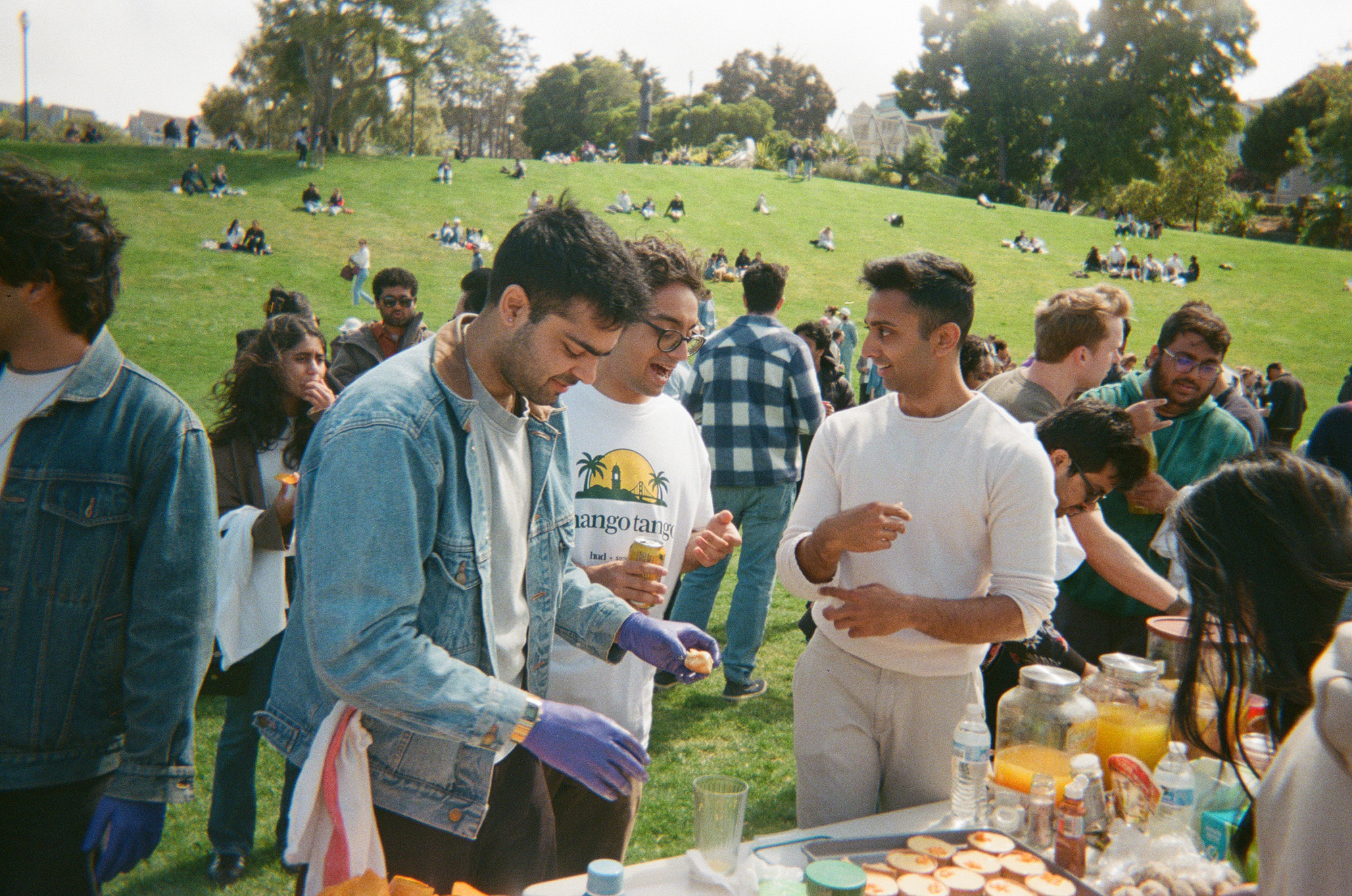 Large group of people eating mangoes in a park.