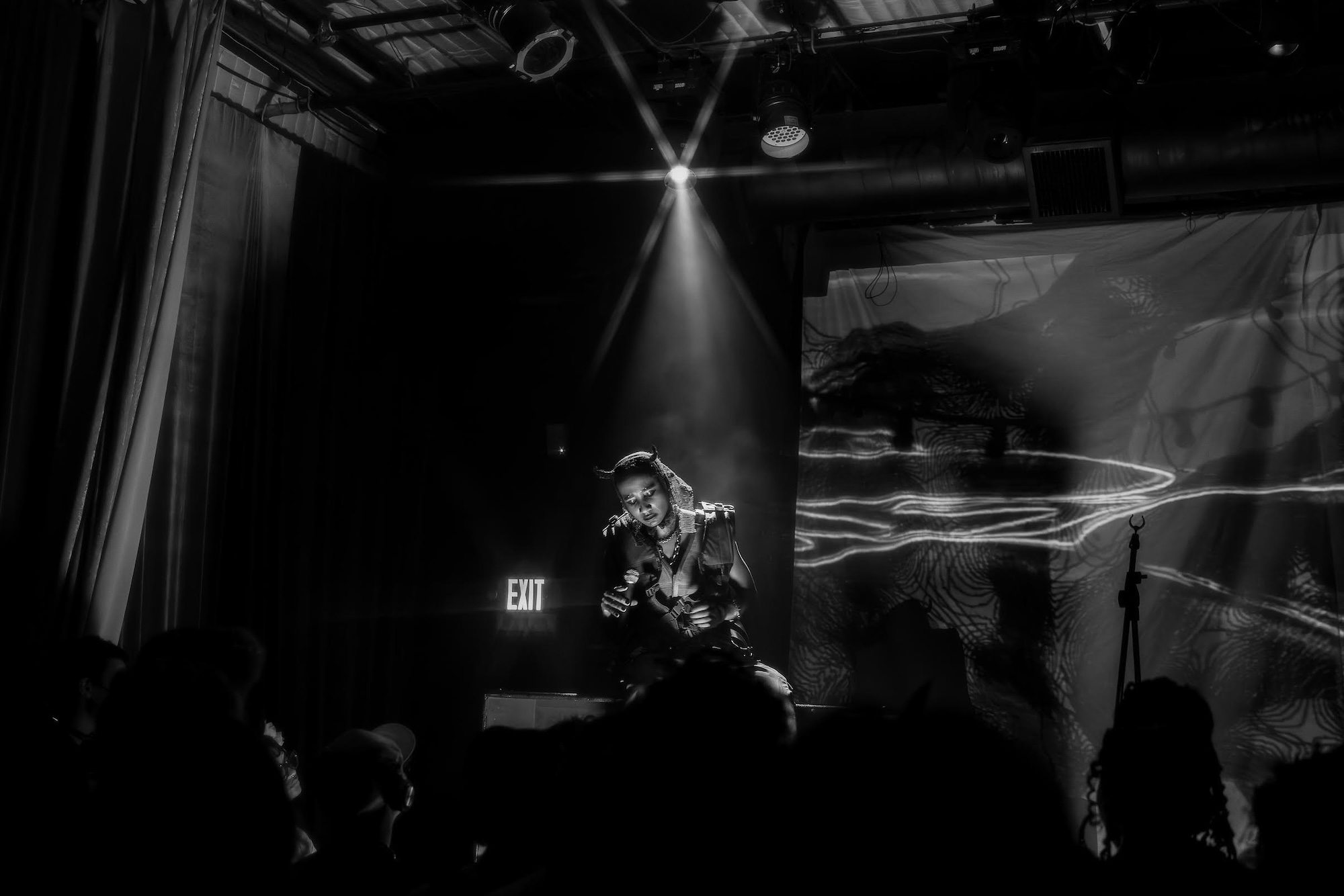 A black and white photo of a person dramatically performing on stage.