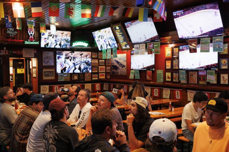 A group of customers sits around a table while TV screens and bright flags hang from the ceiling