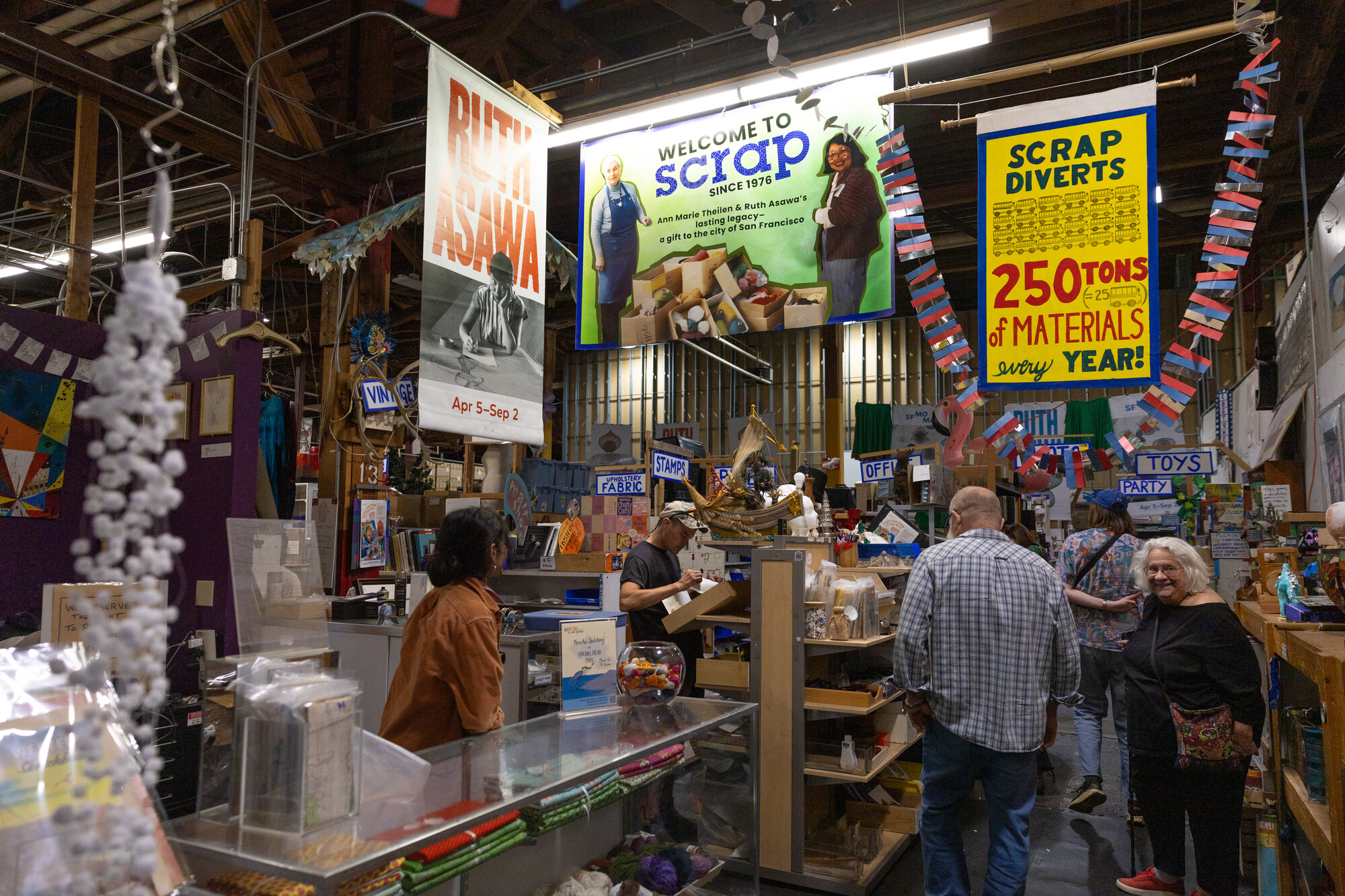 people inside a warehouse surrounded by banners and shelves of art supplies