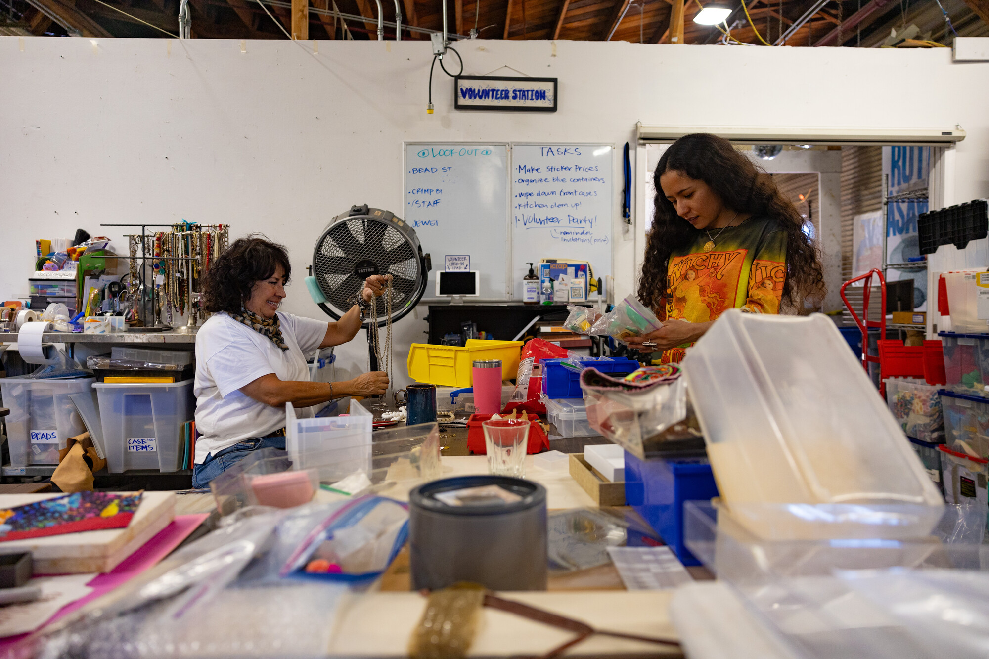 two people handle jewelry and bags in workshop space