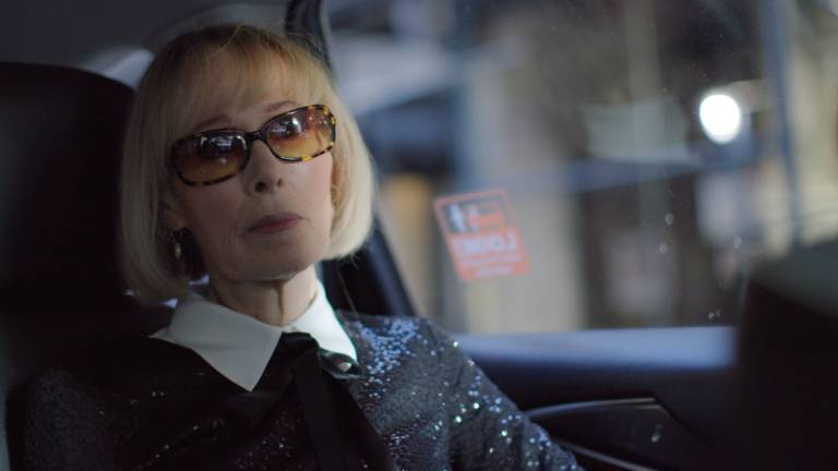 older white woman with blonde bob and sunglasses in car