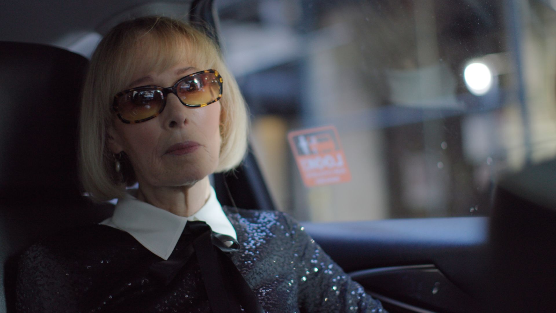 older white woman with blonde bob and sunglasses in car