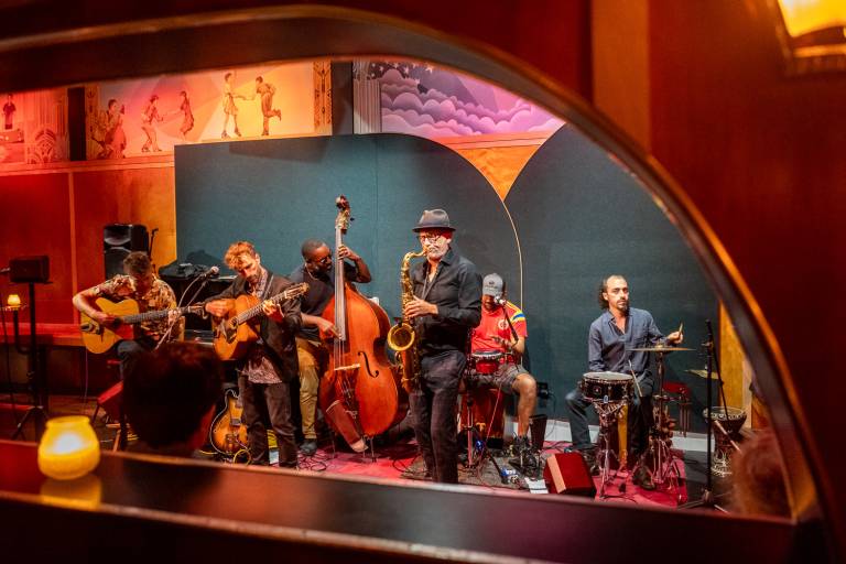 jazz band performs on Art Deco stage with murals behind