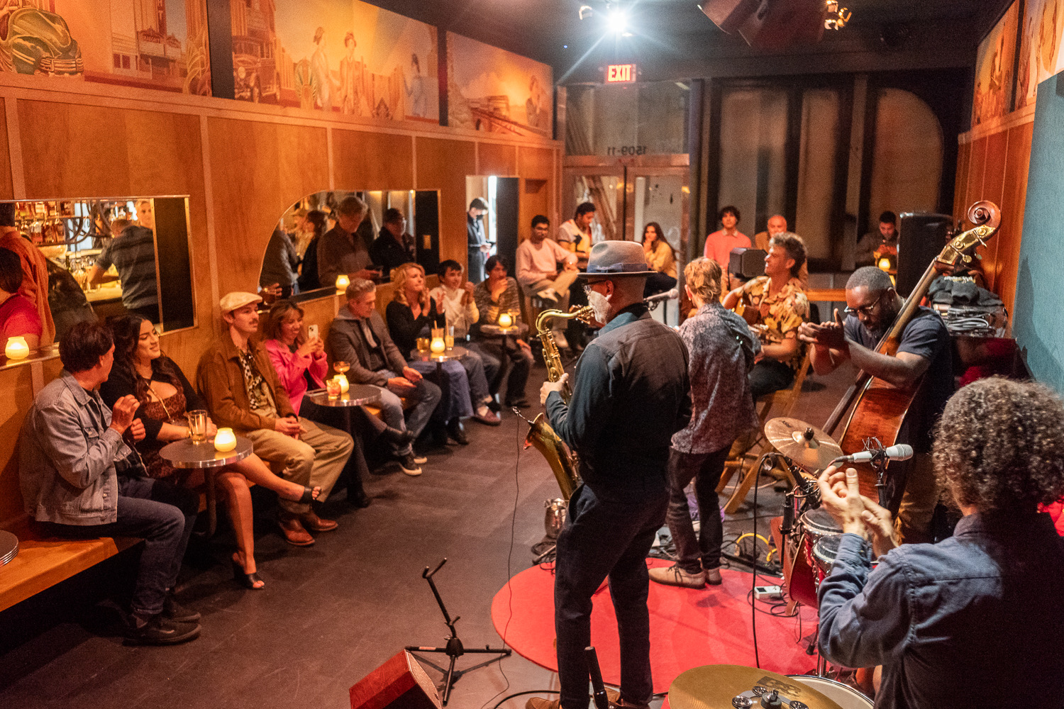 jazz band in small venue with seated audience under Art Deco murals