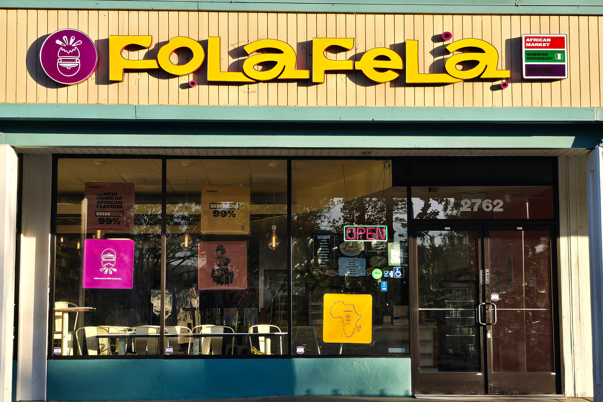 Exterior of a Nigerian restaurant and market. The sign above, in large, stylized yellow letters, reads, "FolaFela."