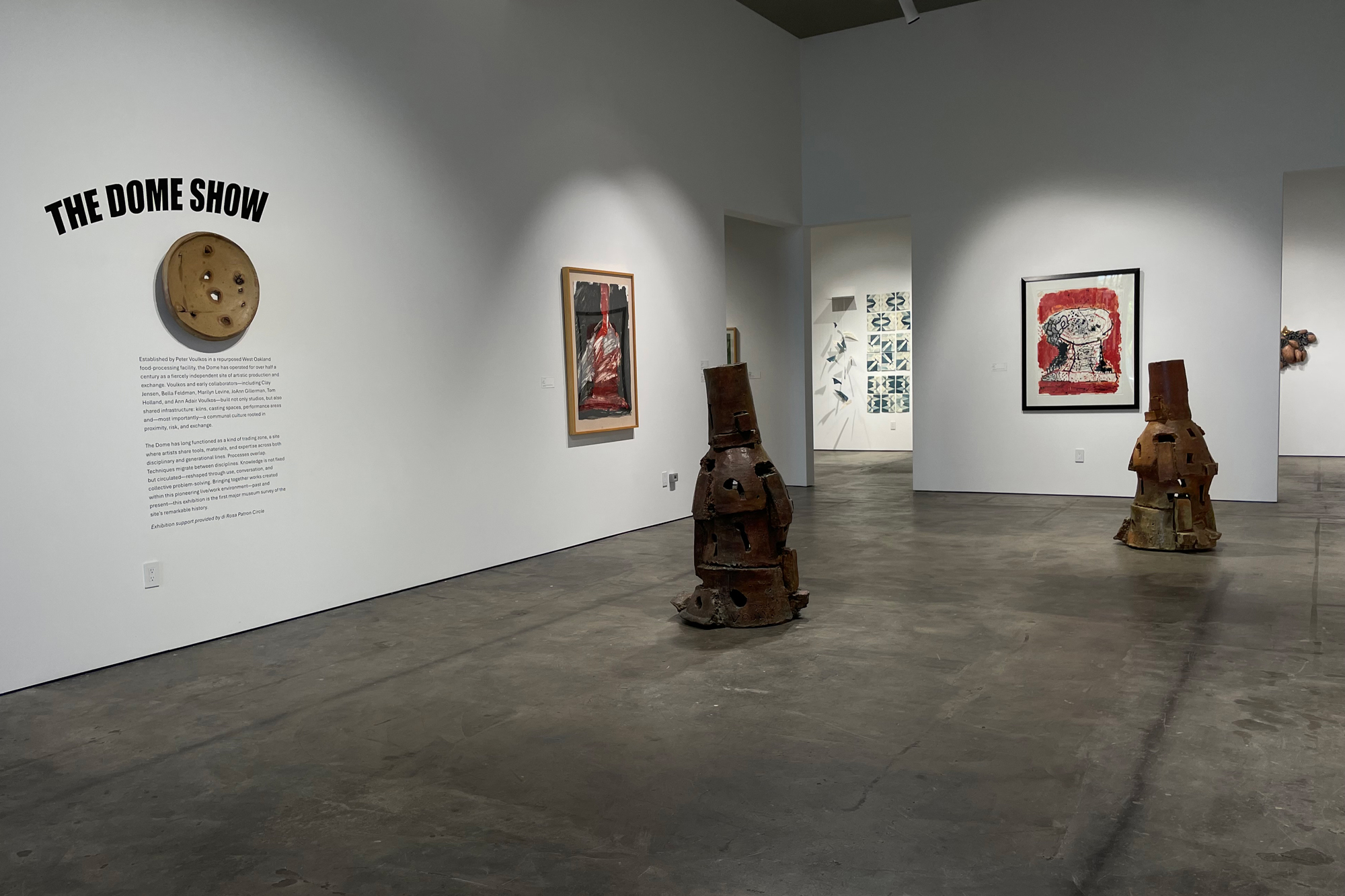 gallery view with sculptures on floor and paintings on walls