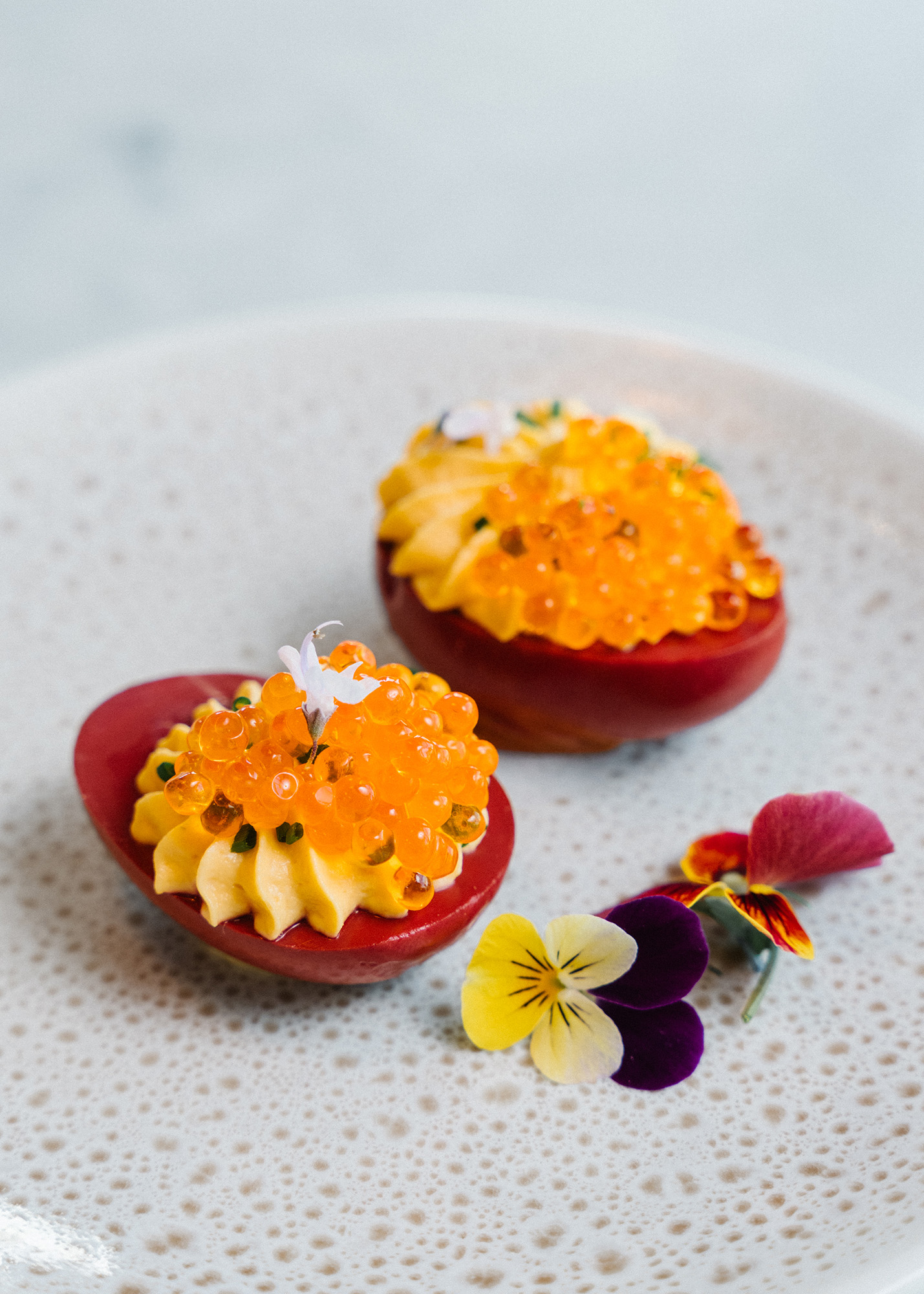 Bright purple deviled eggs topped with orange fish roe.