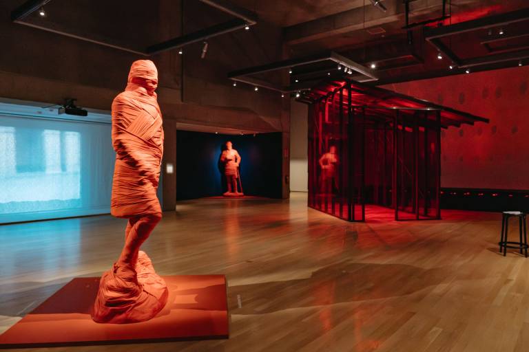 gallery view with wrapped sculptures and a red glass house