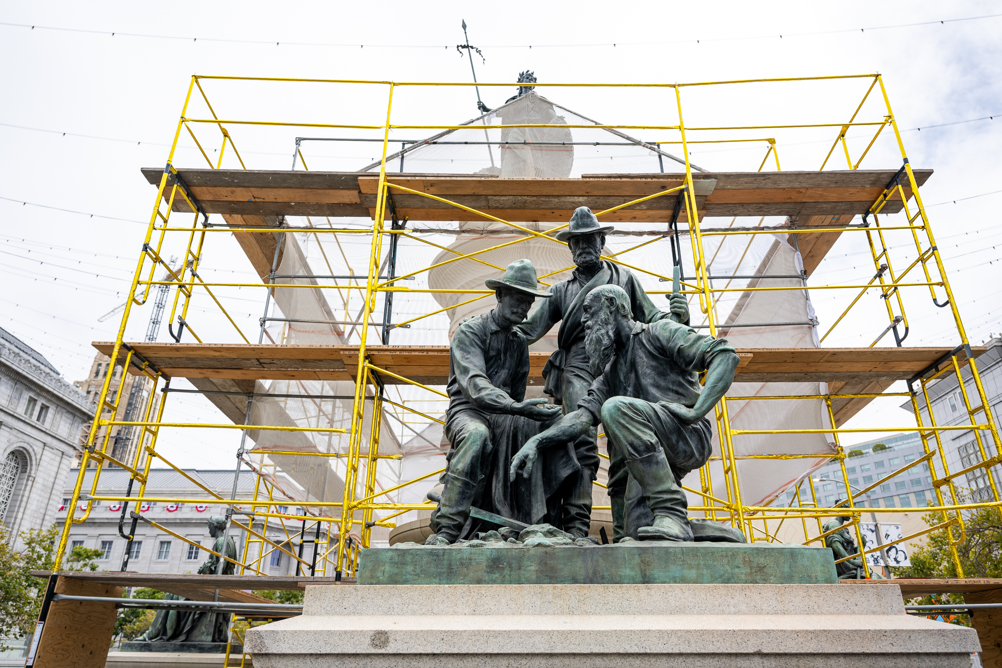 gold-covered scaffolding behind bronze statue of three miners