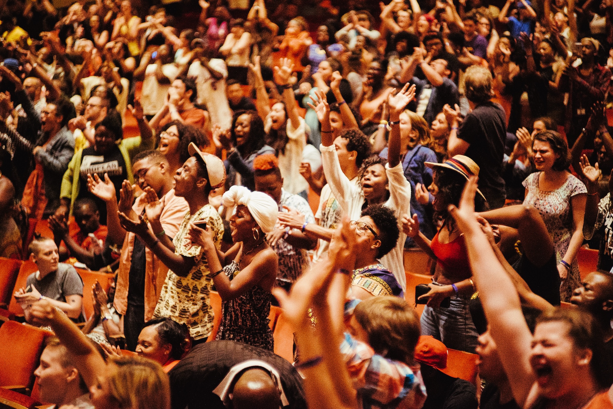A crowd erupting with an ovation after a poetry performance.