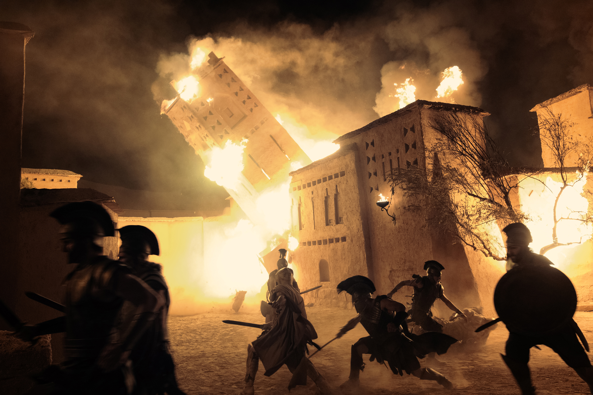 soldiers fight in front of burning ancient city