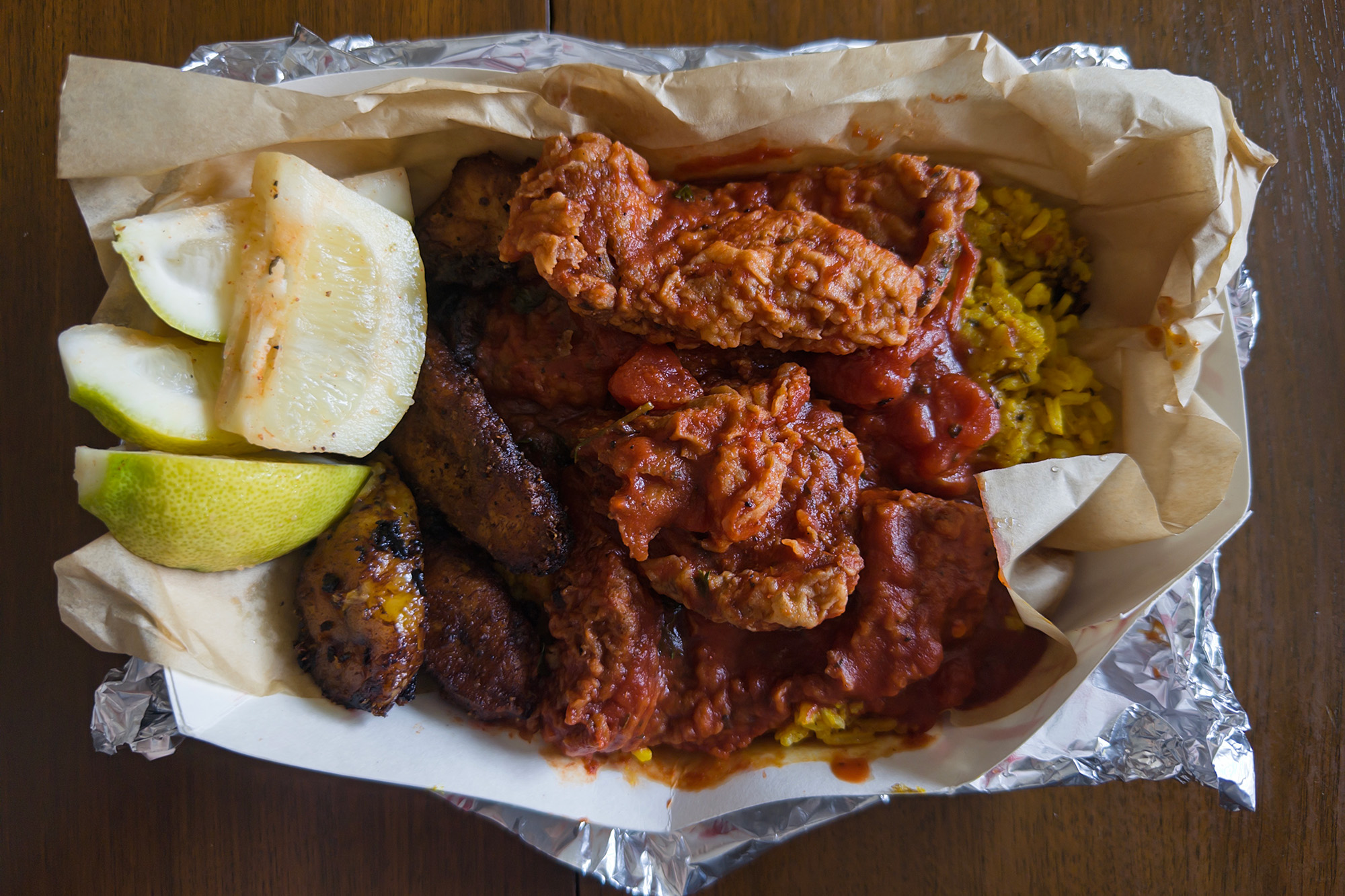 Tomato sauce–soaked pieces of fried catfish in a takeout container.
