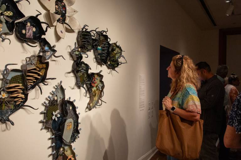 person looks at wall-mounted spiny edged ceramics