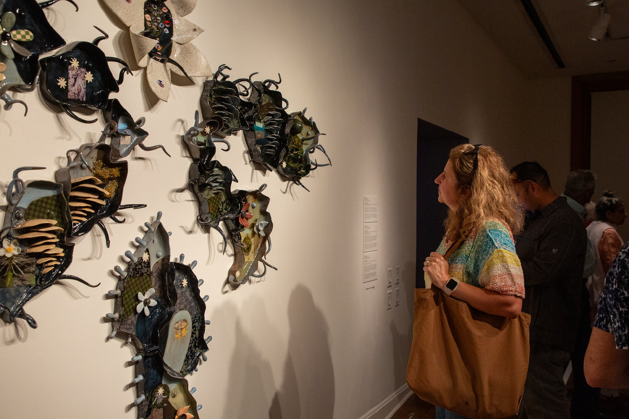 person looks at wall-mounted spiny edged ceramics