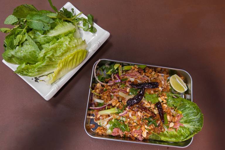 Lao ricd ball salad, served on a metal tray with a plate of fresh herbs and lettuces on the side.