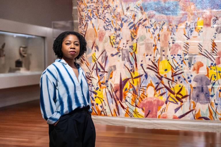 young Black woman stands in front of painting in museum gallery
