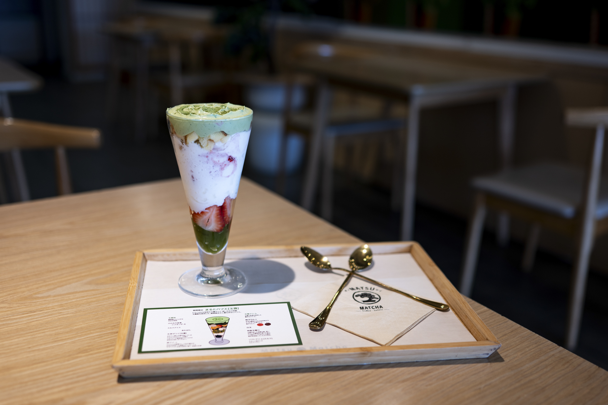 A matcha parfait in a sundae glass, layered with fresh strawberries and ice cream.